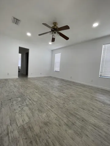 an empty room with windows and fan