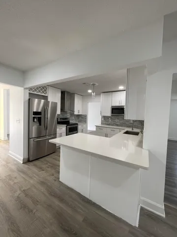 a large white kitchen with a refrigerator a stove a microwave and cabinets