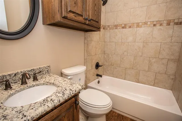 a bathroom with a granite countertop sink a toilet and bathtub