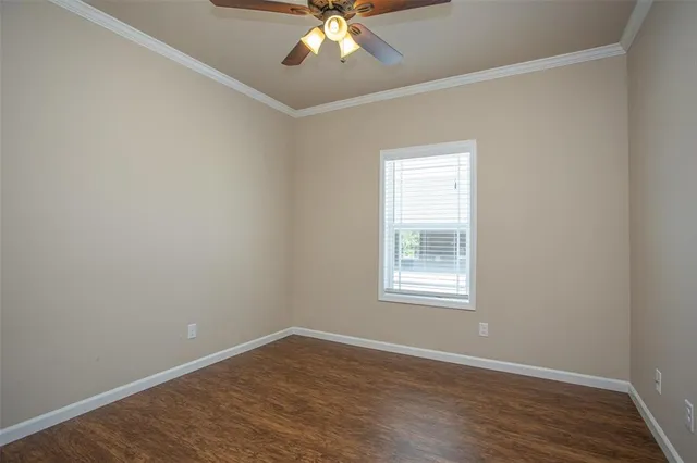 an empty room with wooden floor chandelier fan and windows