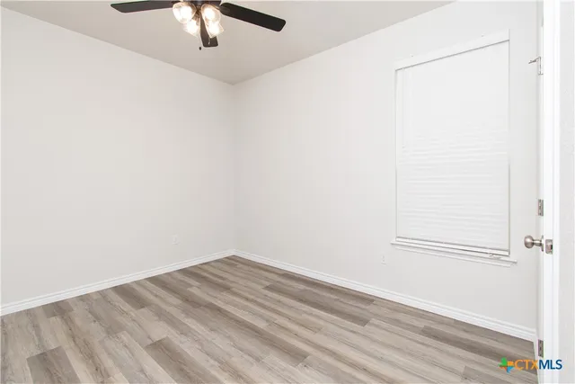 an empty room with a ceiling fan and wooden floor