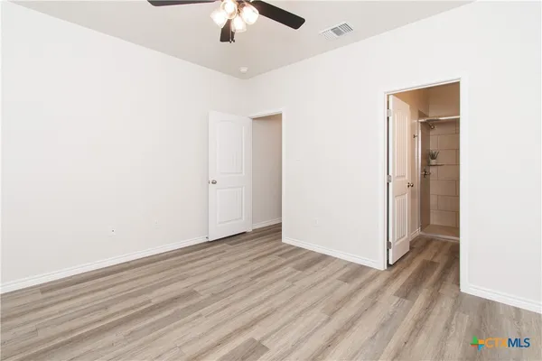 an empty room with wooden floor chandelier fan and closet area