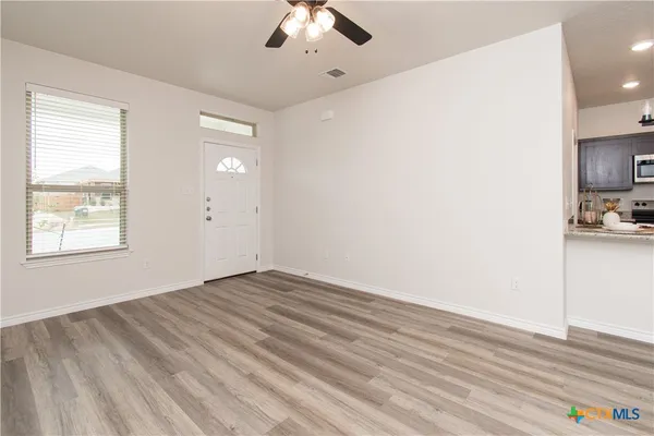 a view of empty room with wooden floor and fan