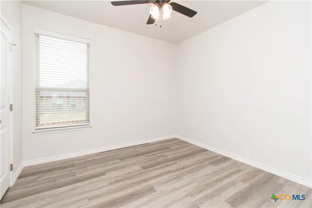 an empty room with a window and a ceiling fan