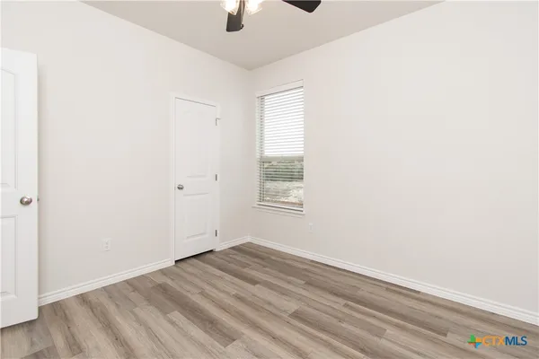 an empty room with ceiling fan and windows