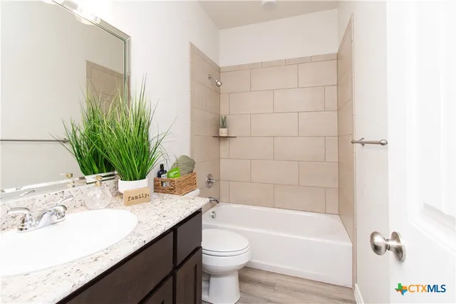 a bathroom with a granite countertop sink a toilet and bathtub