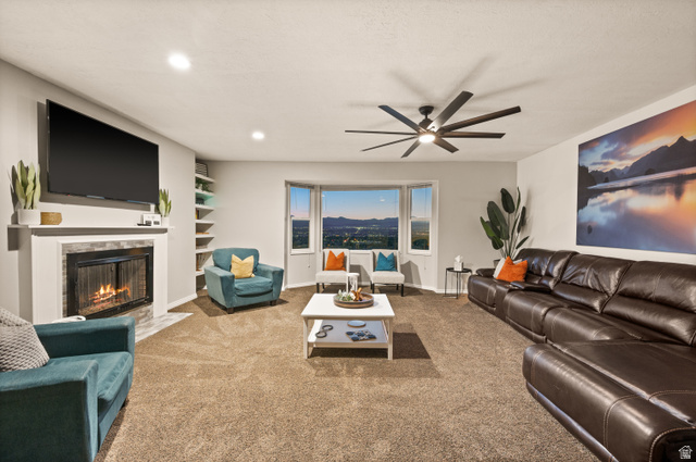 9750 Indian Ridge Drive Sandy, UT 84092 - Photo 11 of 40 Spacious living area featuring a bay window, a ceiling fan, recessed lighting, a fireplace with a stone surround, and built-in shelving