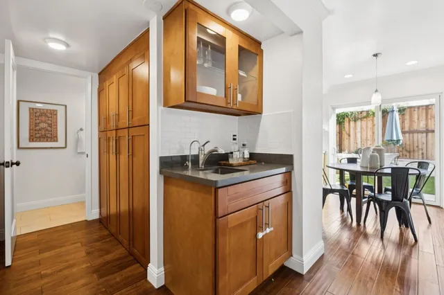 a kitchen with stainless steel appliances granite countertop a stove a refrigerator a kitchen island a dining table and chairs with wooden floor