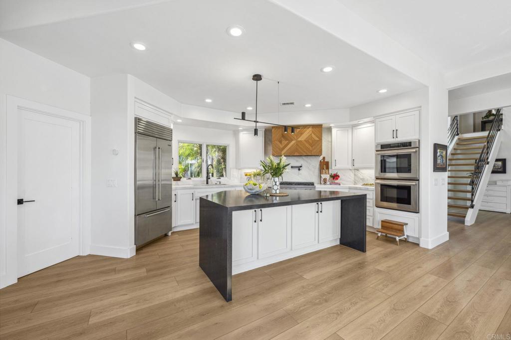 3443 Country Road Fallbrook, CA 92028 - Photo 19 of 71 a kitchen with stainless steel appliances kitchen island granite countertop a refrigerator a stove top oven a sink a dining table and chairs with wooden floor