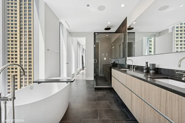 a large white bathroom with a double vanity sink a mirror and a bathtub