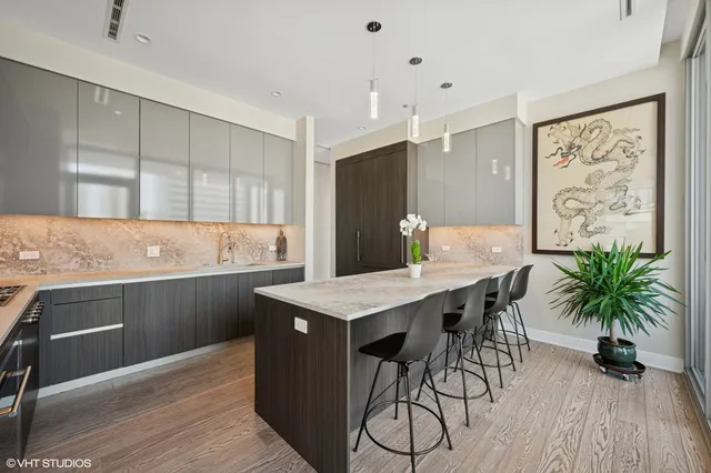 a kitchen with stainless steel appliances kitchen island granite countertop a table chairs sink and cabinets