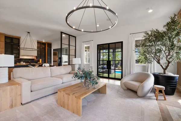 a living room with furniture a chandelier and a large mirror