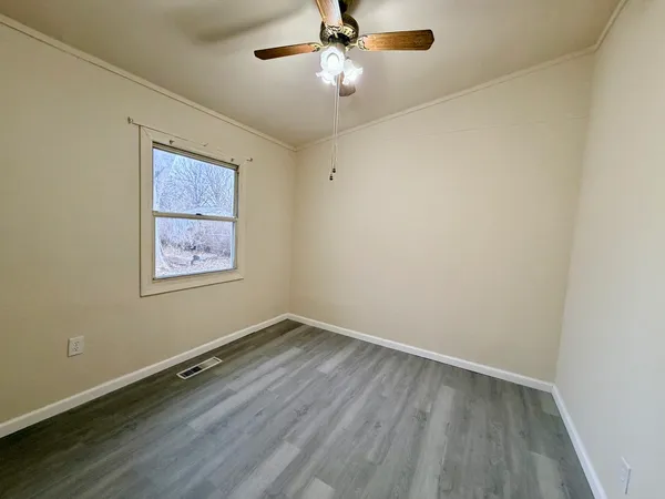 an empty room with a window and a fan