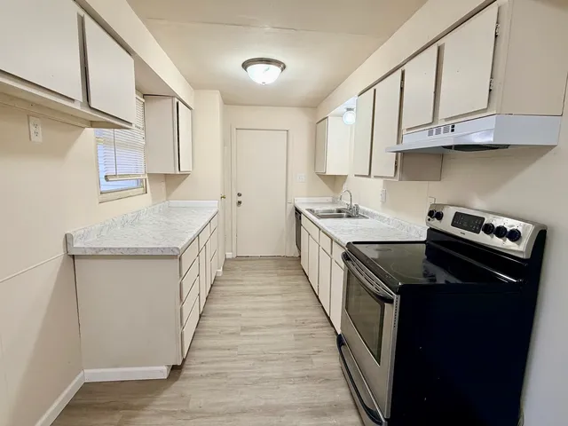 a kitchen with stainless steel appliances granite countertop a sink stove and cabinets