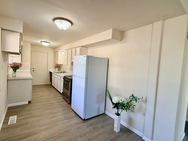 a kitchen with white cabinets and wooden floor
