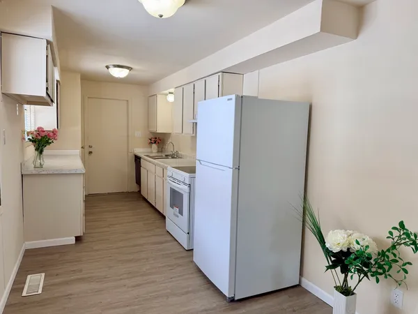 a kitchen with stainless steel appliances a refrigerator and a wooden floor