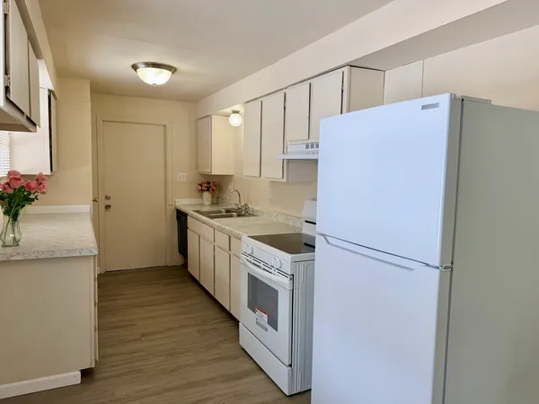 a kitchen with a refrigerator a sink and wooden floor