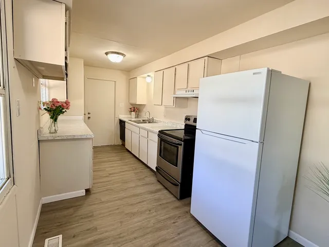 a kitchen with sink a refrigerator and white cabinets