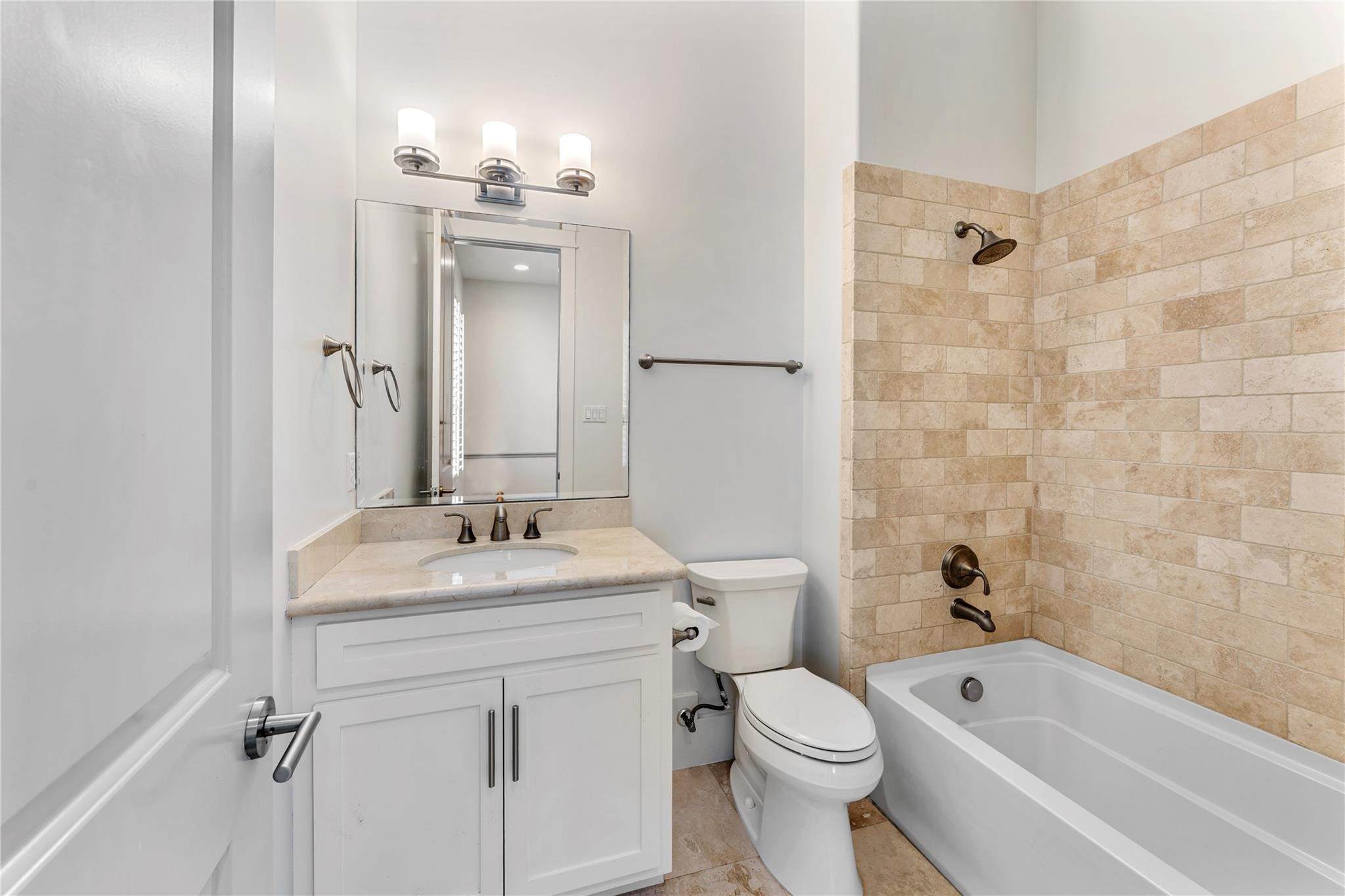 4938 Edison Park Lane Houston, TX 77081 - Photo 43 of 49 This bathroom features a clean,
modern design with a white
vanity, a spacious mirror, and
warm-toned tiled shower. It
includes brushed metal fixtures
and a bathtub, creating a
welcoming and functional space.