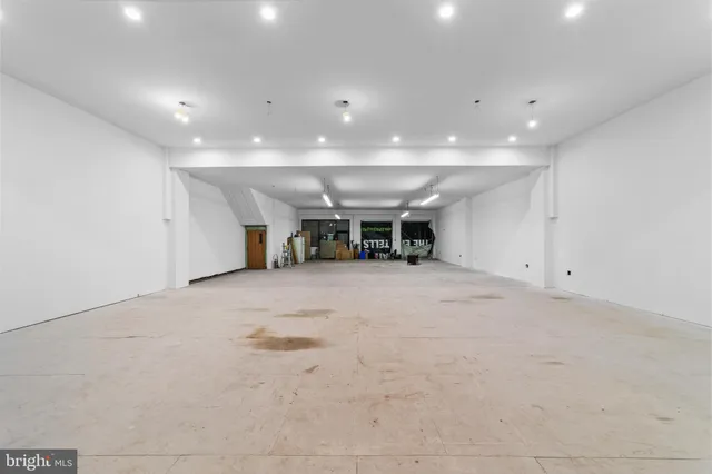 a view of an empty room with kitchen and a window