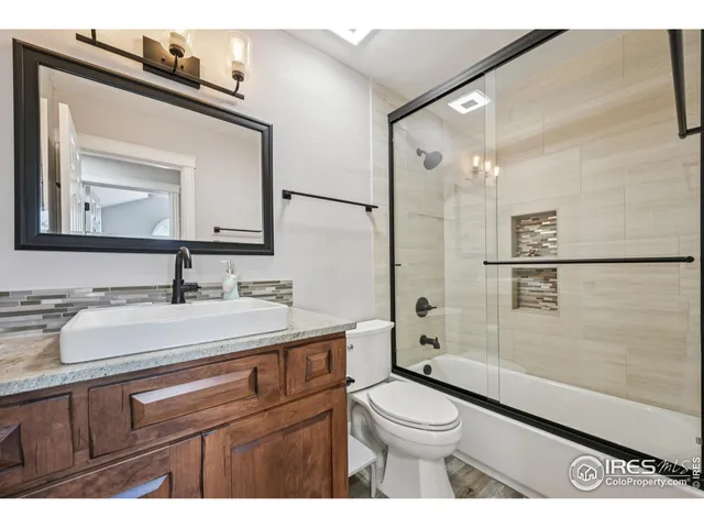 a bathroom with a toilet a sink a mirror and shower
