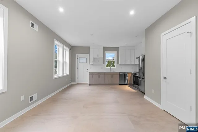a view of a big room with windows and chandelier fan