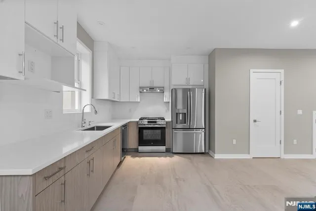 a kitchen with stainless steel appliances granite countertop a refrigerator sink and stove
