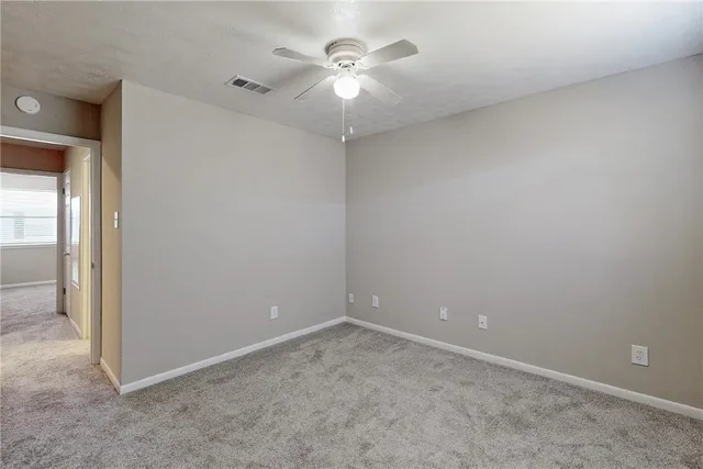 an empty room with a chandelier fan and windows