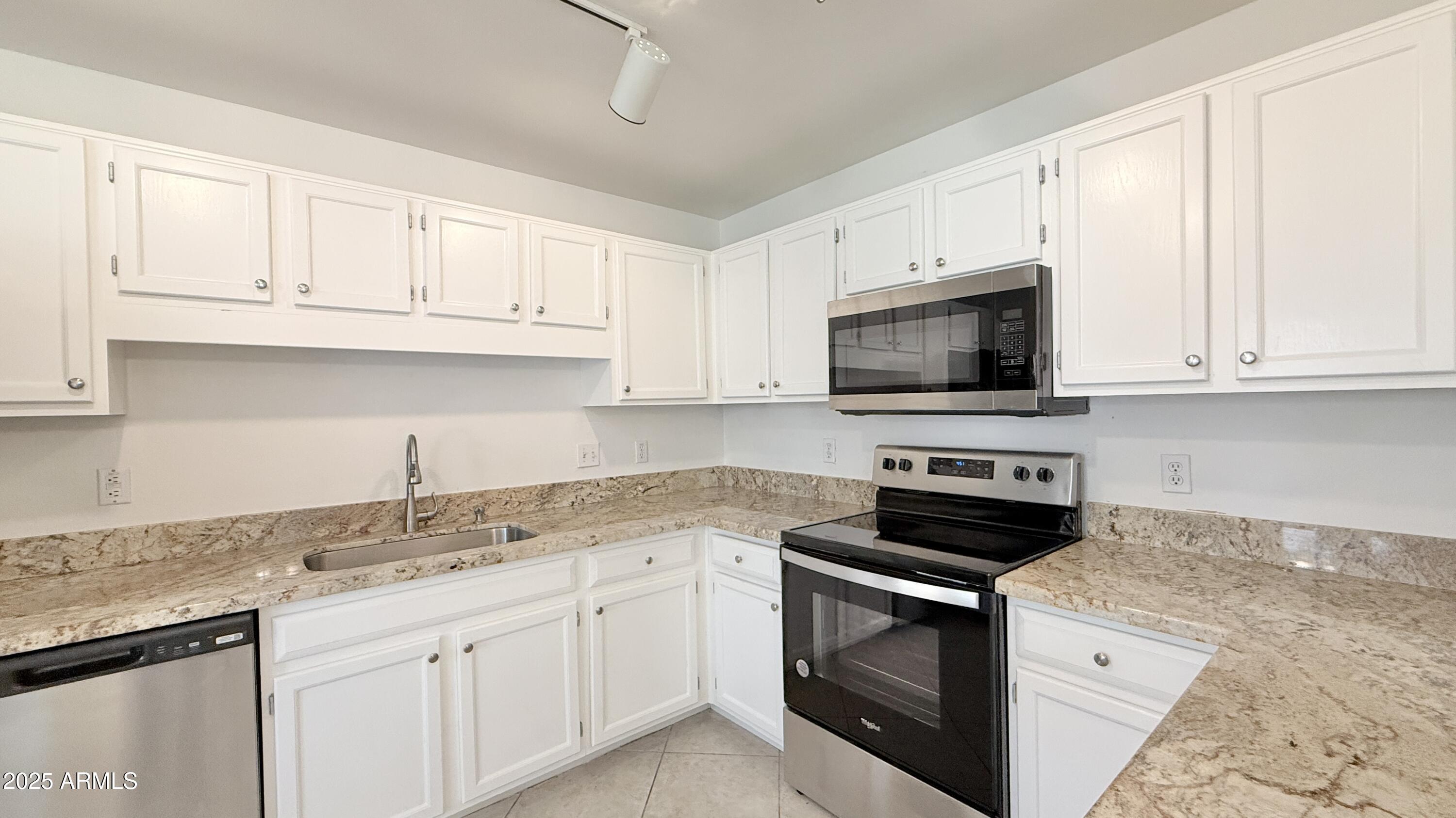 15050 North Thompson Peak Parkway, Unit 1012 Scottsdale, AZ 85260 - Photo 3 of 49 a kitchen with granite countertop white cabinets and stainless steel appliances
