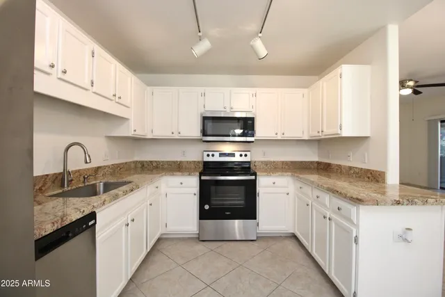 a kitchen with granite countertop a sink dishwasher a stove and a refrigerator