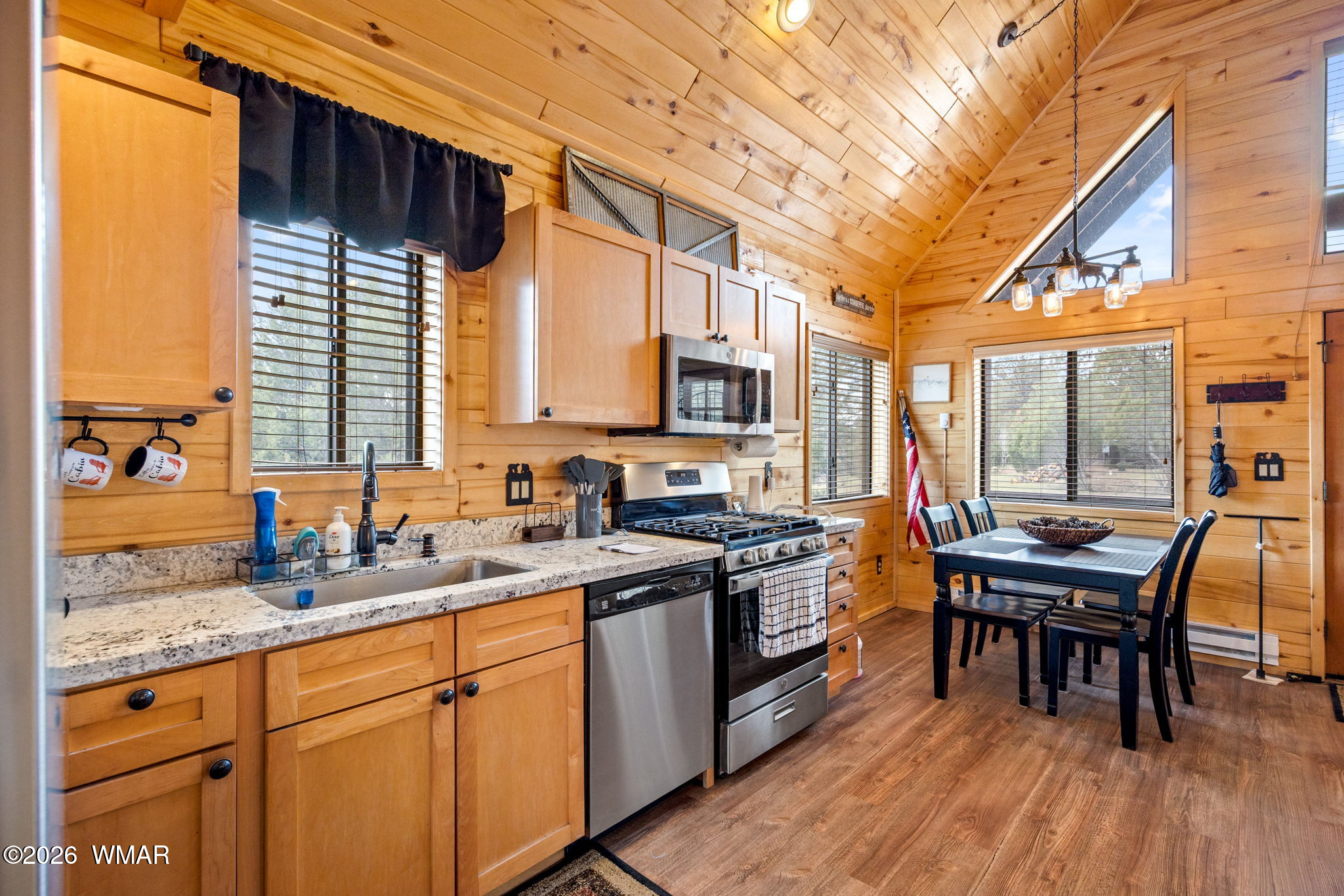 2741 Elk Trail Road Overgaard, AZ 85933 - Photo 44 of 68 a kitchen with stainless steel appliances granite countertop a stove a sink dishwasher a dining table and chairs with wooden floor