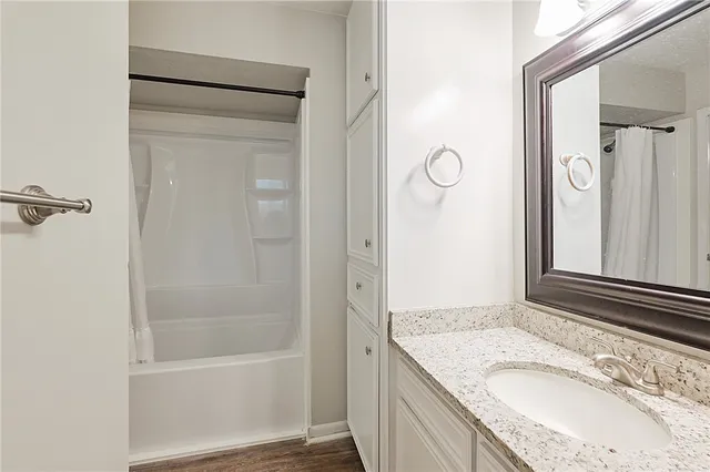 a bathroom with a granite countertop sink a mirror and shower