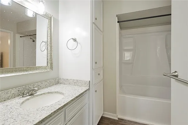 a bathroom with a granite countertop sink a mirror and a bathtub