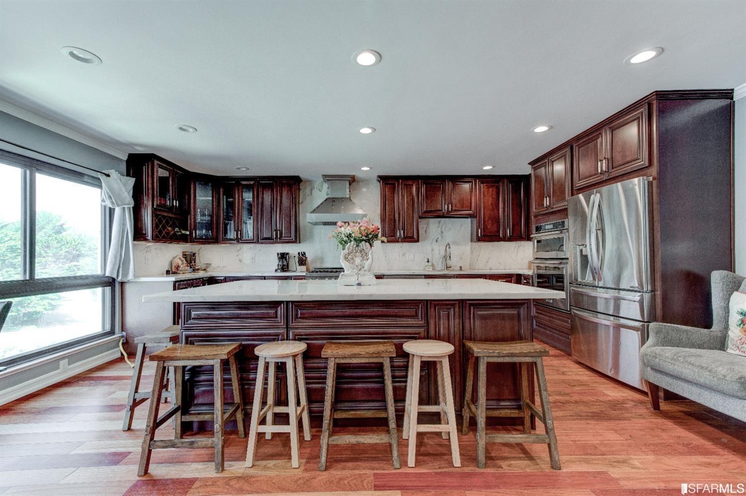 a kitchen with stainless steel appliances granite countertop a dining table chairs refrigerator and cabinets