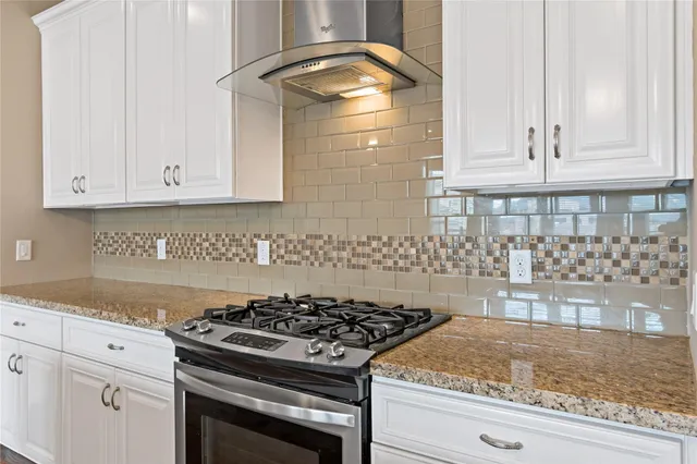 a kitchen with granite countertop a stove and white cabinets