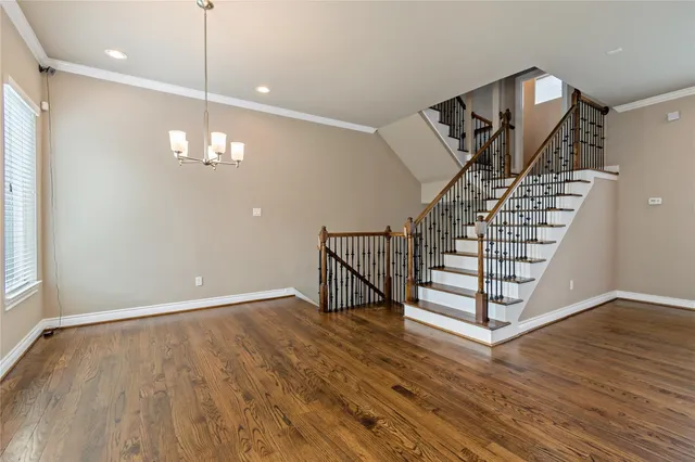 an empty room with wooden floor and staircase