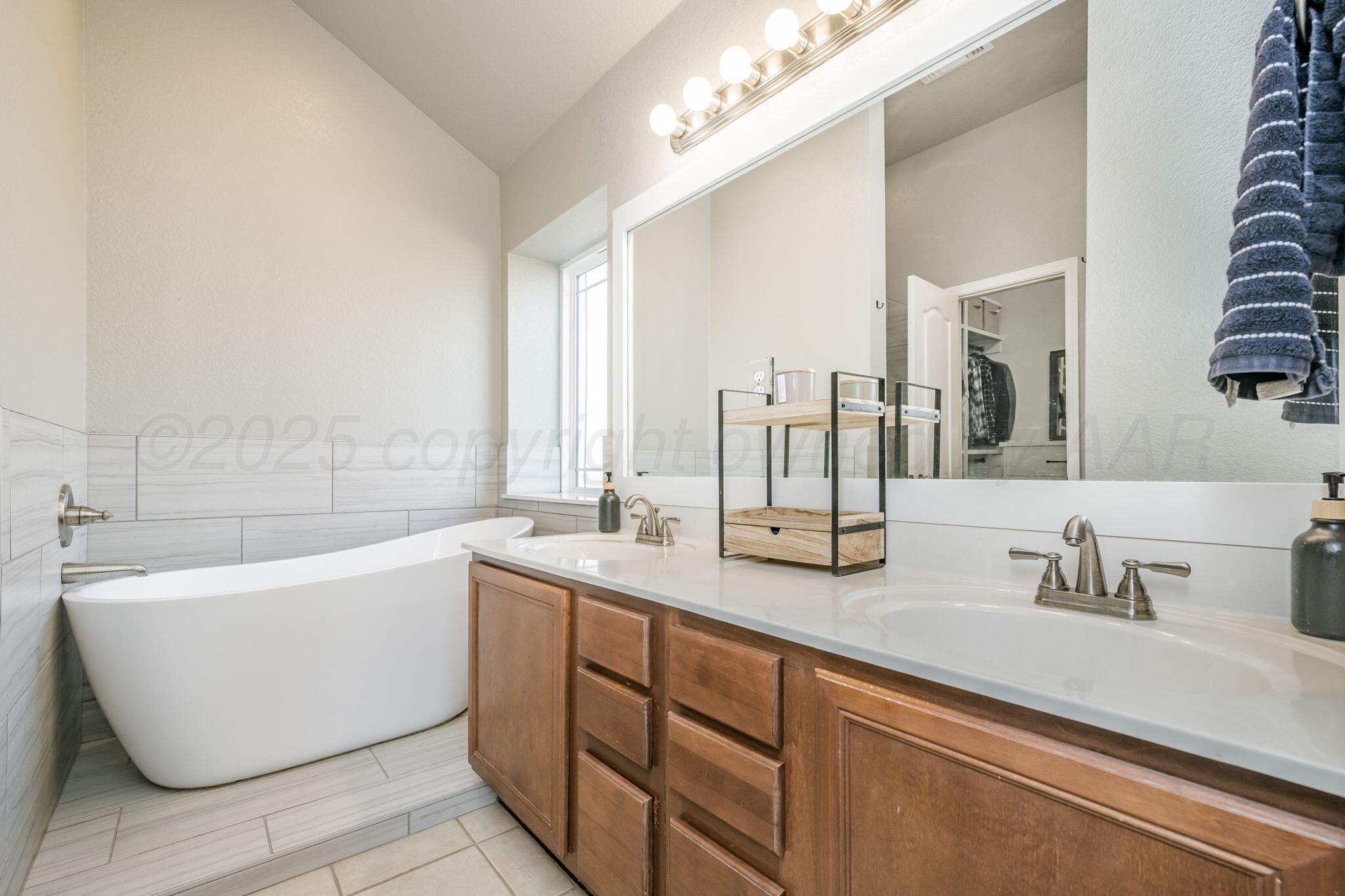 1404 Southwest 61st Avenue Amarillo, TX 79118 - Photo 17 of 30 a bathroom with a double vanity sink and a bathtub