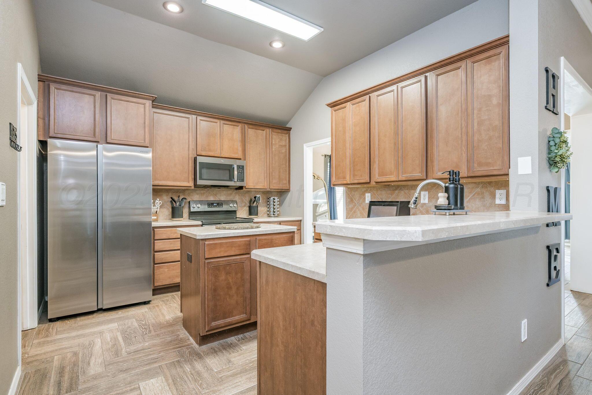 1404 Southwest 61st Avenue Amarillo, TX 79118 - Photo 9 of 30 a kitchen with stainless steel appliances granite countertop a refrigerator a sink a stove and white cabinets with wooden floor