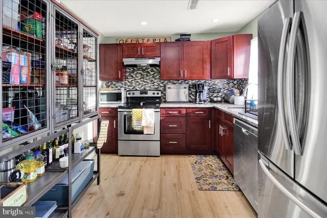 a kitchen with stainless steel appliances kitchen island granite countertop a refrigerator and a wooden cabinets