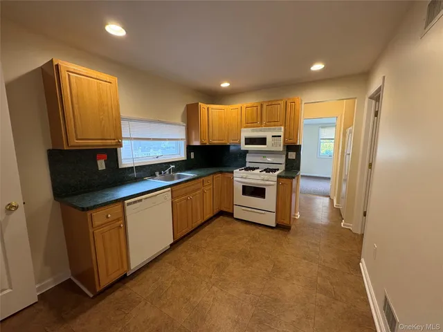 a kitchen with stainless steel appliances a sink a stove a microwave a refrigerator a counter top space and cabinets