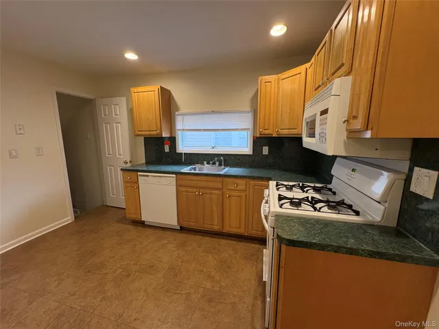 a kitchen with granite countertop a sink stove and cabinets