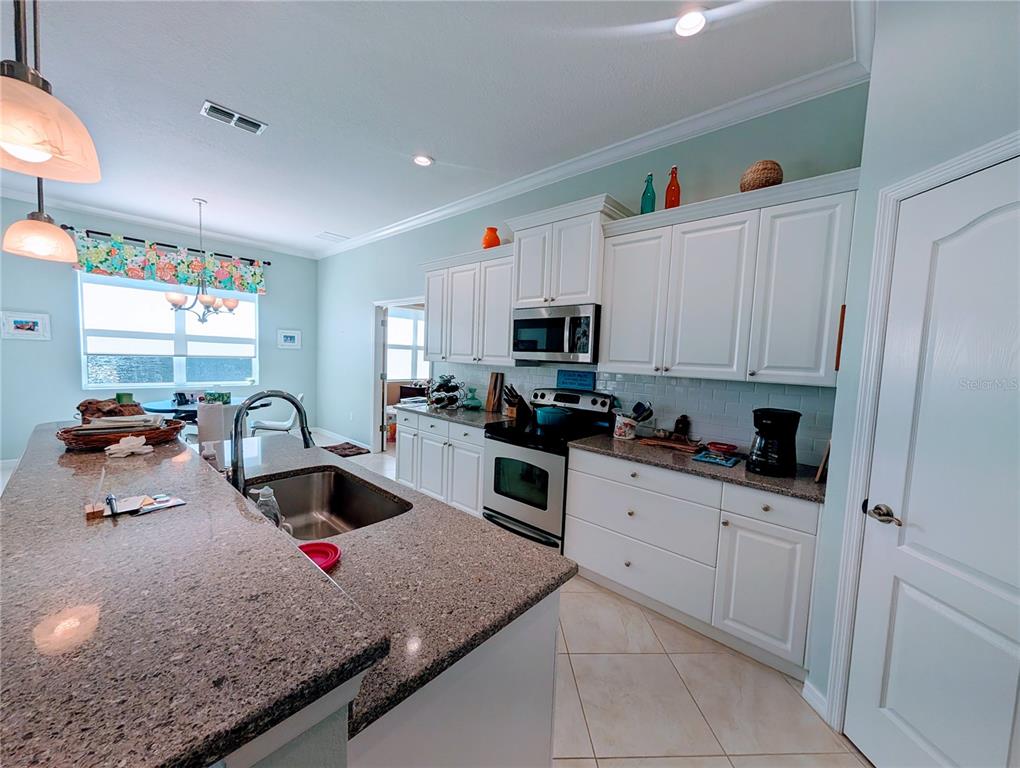 343 Marsh Creek Road Venice, FL 34292 - Photo 9 of 30 a kitchen with granite countertop a sink white cabinets and appliances