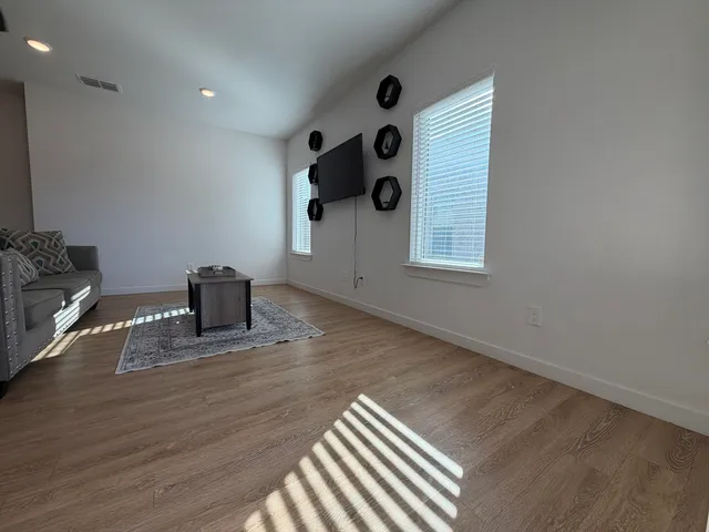 an empty room with wooden floor and windows
