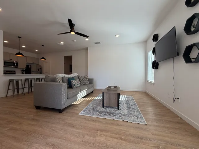 a living room with couches and kitchen view with wooden floor