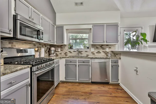 a kitchen with stainless steel appliances granite countertop a stove a refrigerator and a microwave