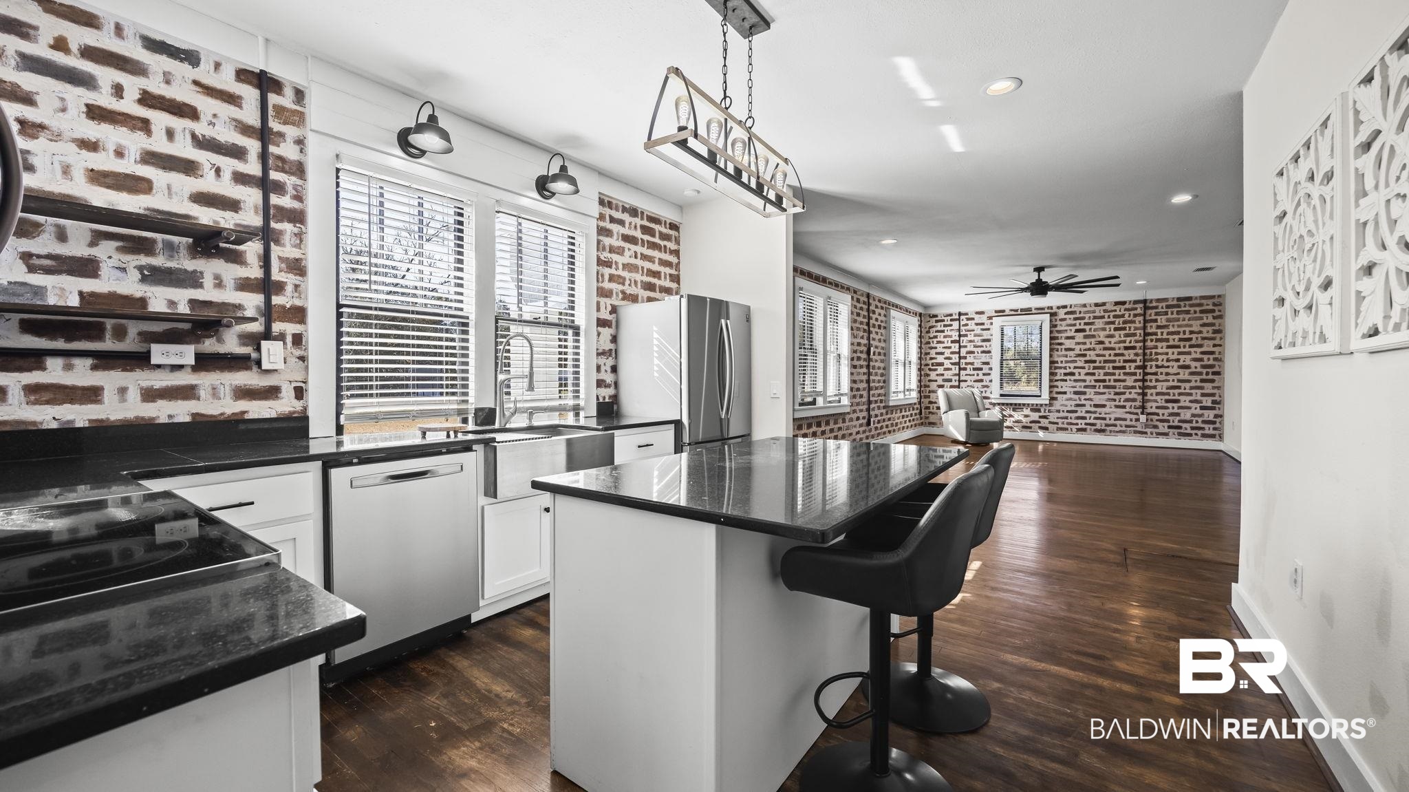 24701 Highway 98 Elberta, AL 36530 - Photo 5 of 32 Kitchen with brick wall, a kitchen island, decorative light fixtures, a breakfast bar, and stainless steel appliances