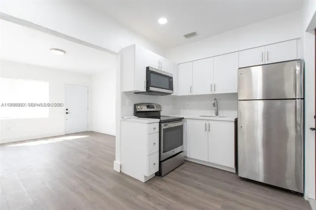 a kitchen with a refrigerator stove and white cabinets
