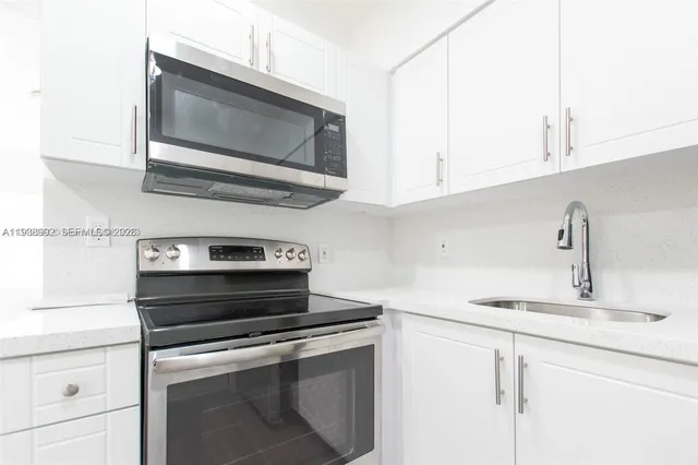 a kitchen with stainless steel appliances granite countertop white cabinets and stove