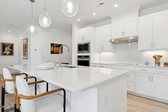 a kitchen with kitchen island a stove a microwave a dining table and chairs with wooden floor