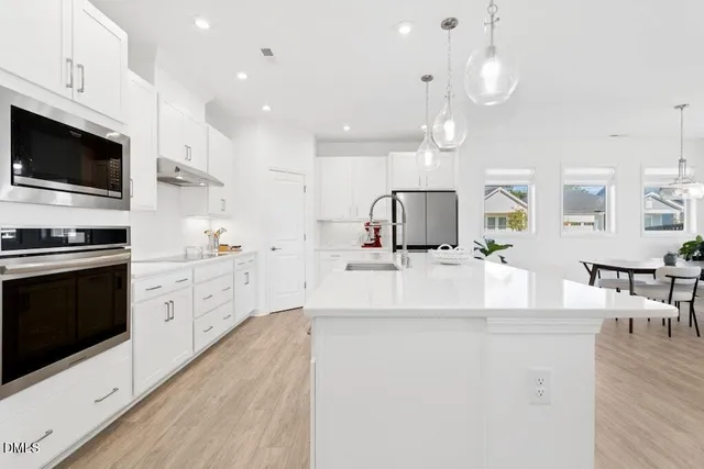 an open kitchen with white cabinets and stainless steel appliances